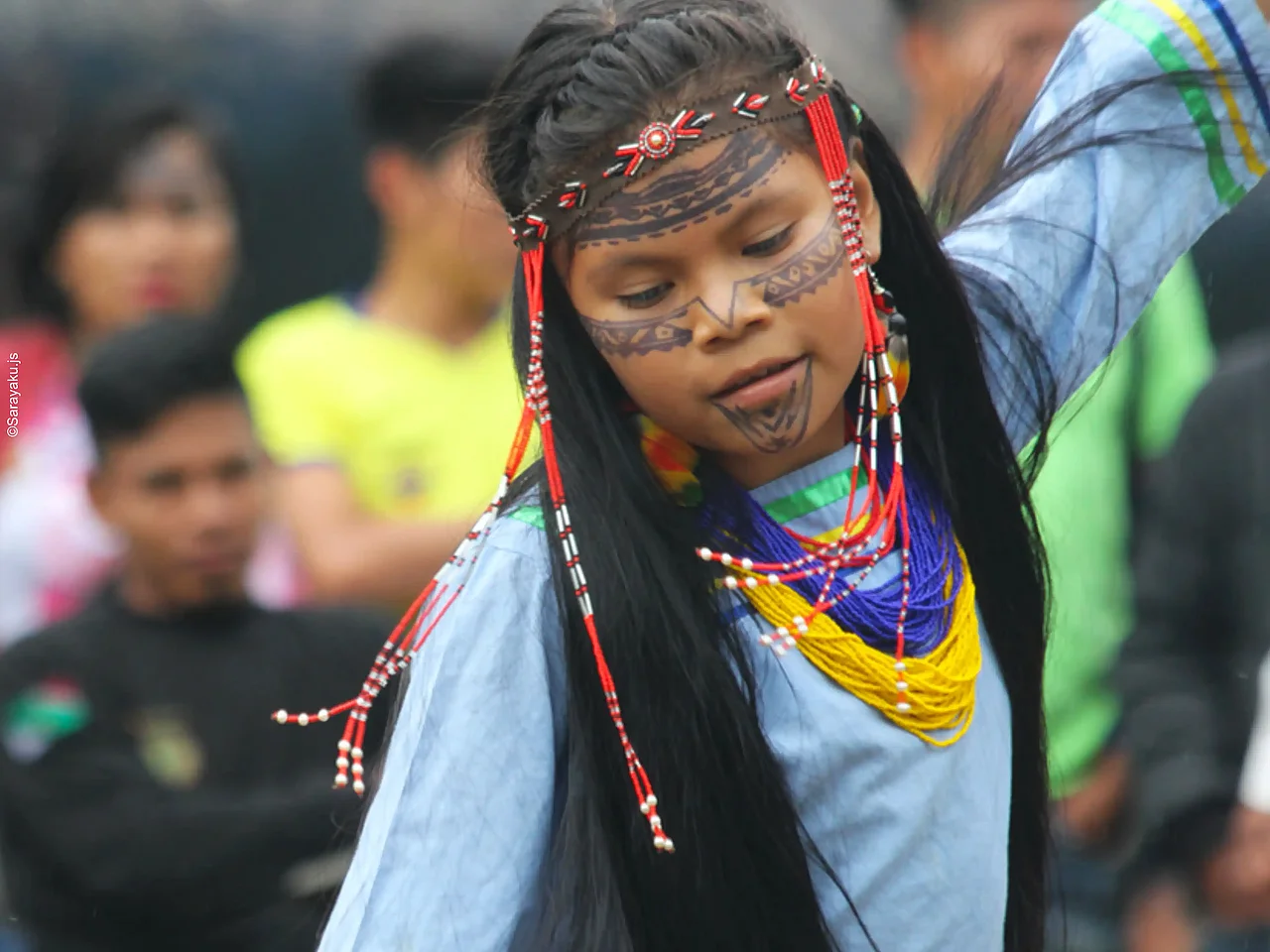 Ein indigenes Mädchen in traditioneller Tracht ist am Tanzen.
