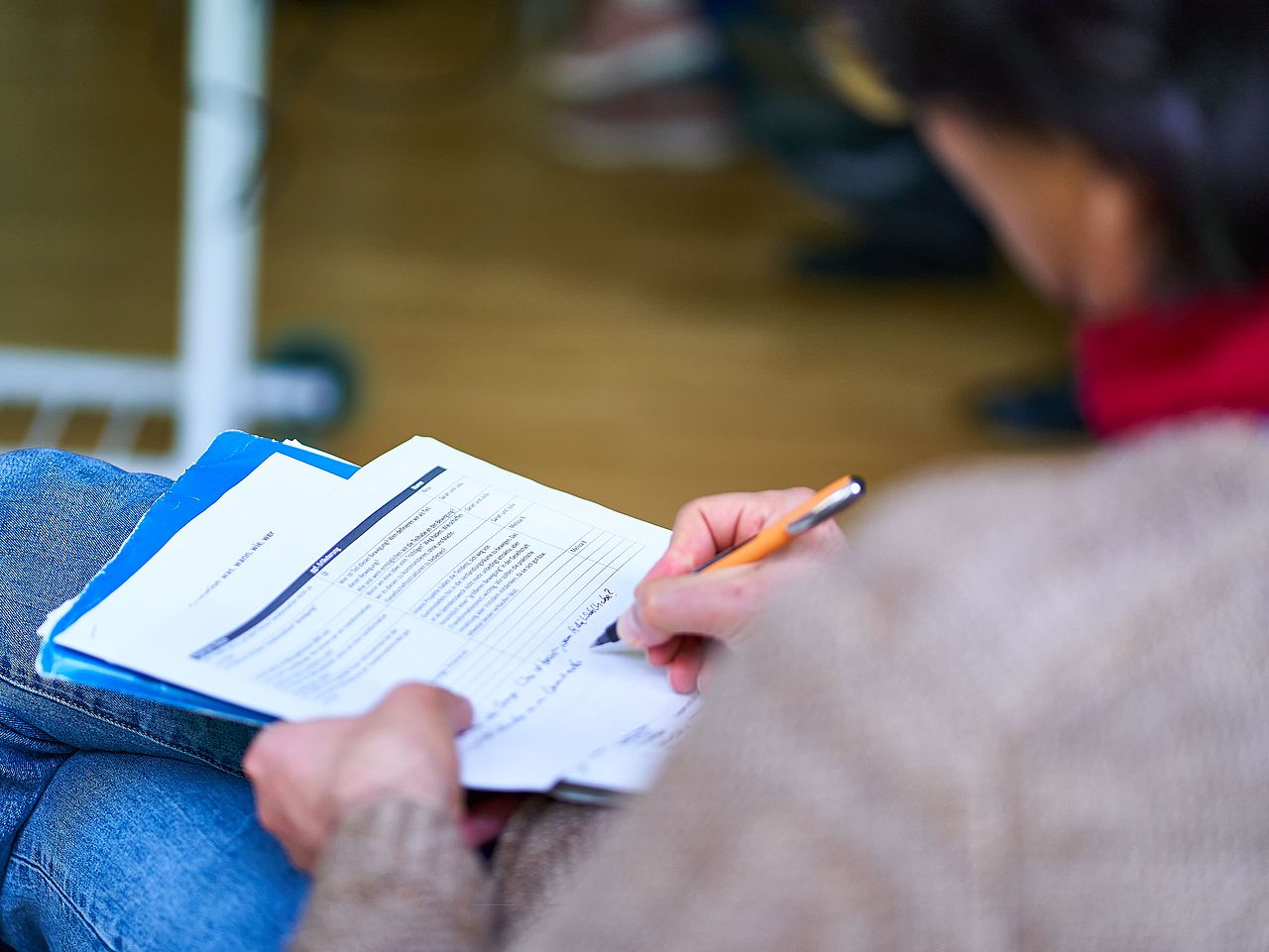 Ein sitzender Mensch der auf Dokumente schreibt