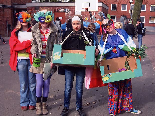 Schülerinnen Tragen Masken, die an Tiere aus dem Regenwald erinnern. Aktionswettbewerb einer Bremer Grundschule.