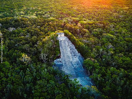 Die Drohnenaufnahme zeigt die Ruinen von Cobá inmitten des grünen Waldes.