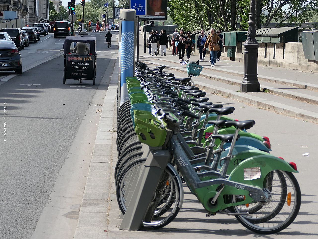 Mehrere Leihräder stehen ordentlich abgestellt in Fahrradständern am Straßenrand. 