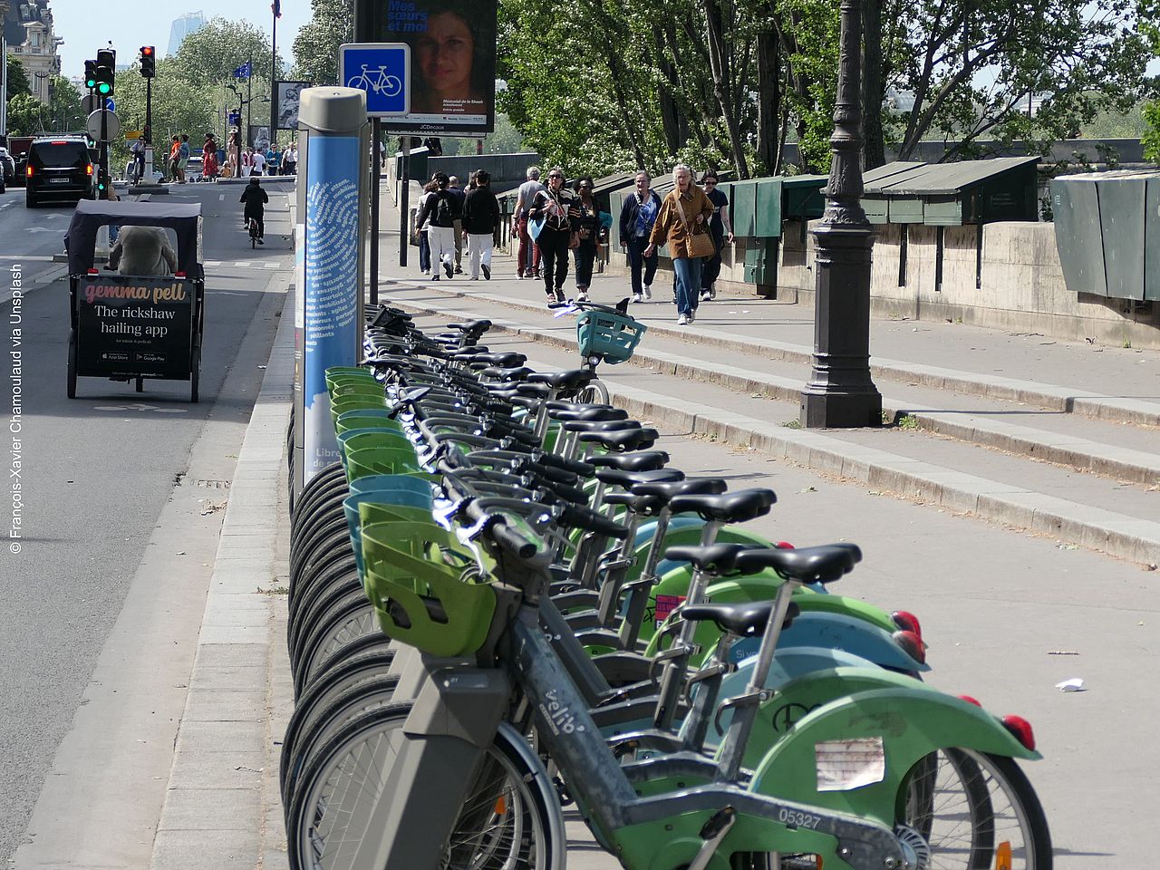 Mehrere Leihräder stehen ordentlich abgestellt in Fahrradständern am Straßenrand. 