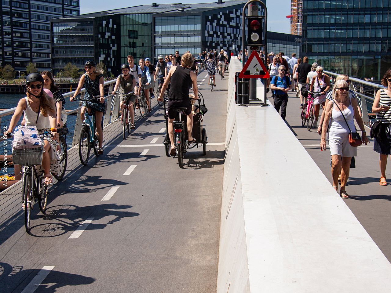 Eine Fahrradbrücke über einem Fluss in Kopenhagen. Zwei Radfahrer*innen fahren gerade auf der Brücke und aus dem Bild heraus.