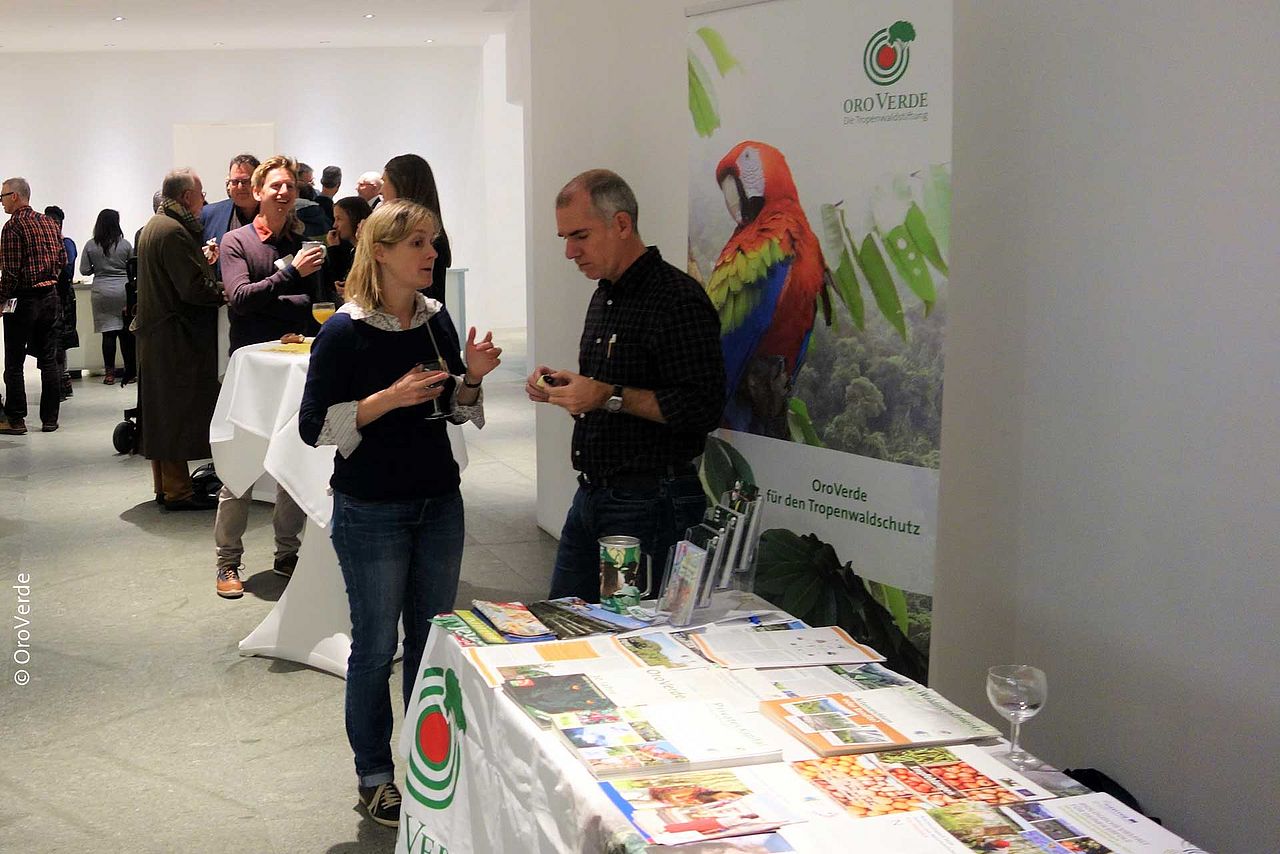 Im Foyer des Veranstaltungsortes unterhielt sich das Publikum angeregt über Regenwaldschutz und Wirtschaftlichkeit. Den OroVerde-Infostand betreute an diesem Abend Michael Metz. ©OroVerde