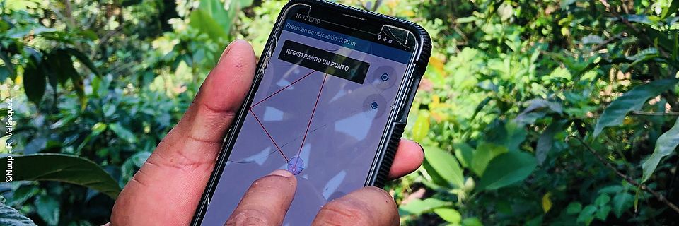 Eine Person hält ein Handy, auf der die App Sirio geöffnet ist. Eine Landkarte ist in der App geöffnet.