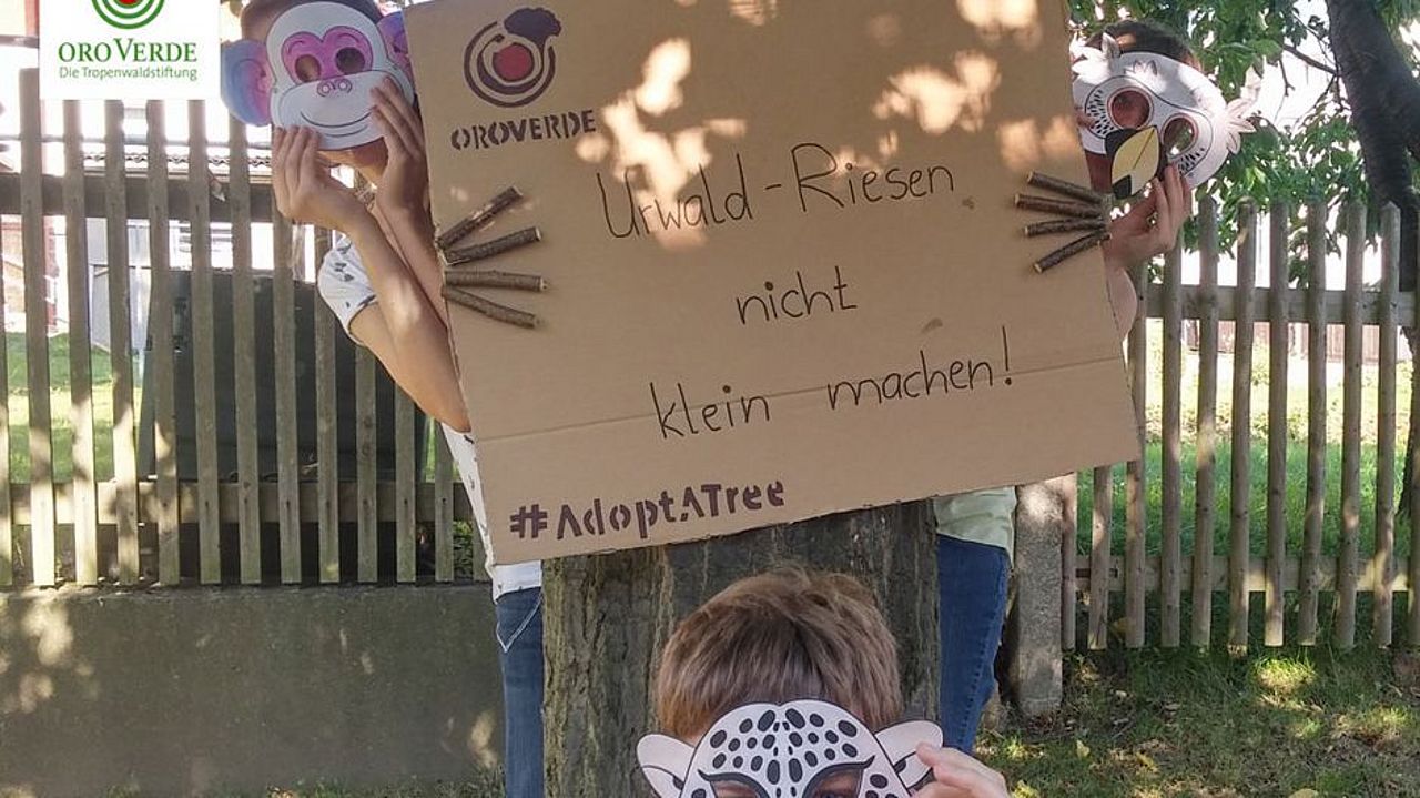 Schüleraktion Adopt a tree Schüler mit Schild und Tiermasken.