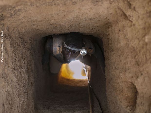 Ein Arbeiter klettert ohne Schutzkleidung durch einen Schacht in einer Goldmine.