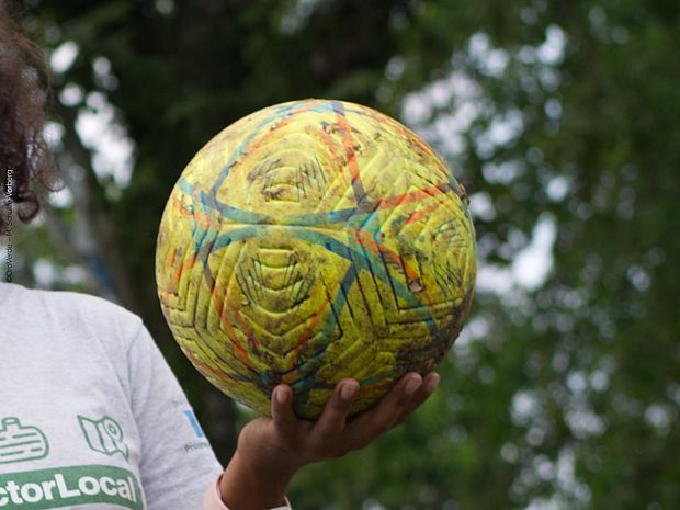 Neben der Schule rennen johlend Jugendliche über ein Fußballfeld. Lachend schießen sie sich die Bälle zu. 