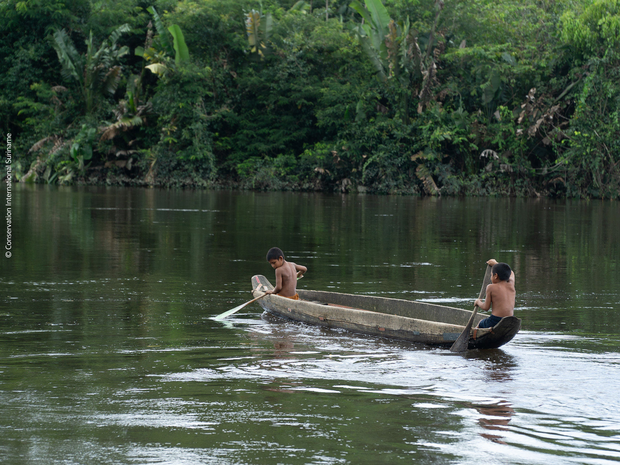 Zwei Kinder fahren auf einem quecksilberbelasteten Fluss Kanu.