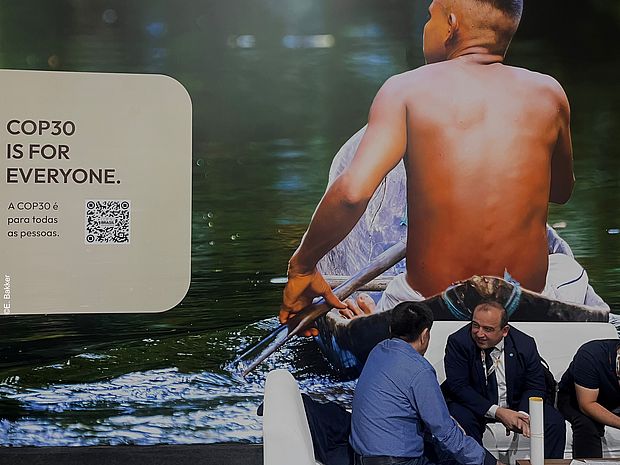 Eine Fotomontage: Ein junger augenscheinlich indigener Mann von hinten in einem Holz-Kanu. Unten rechts ein kleines Bild einer hitzige Debatte zwischen weiß gelesenen Personen. Oben links ist zu lesen: "COP30 is for everyone"