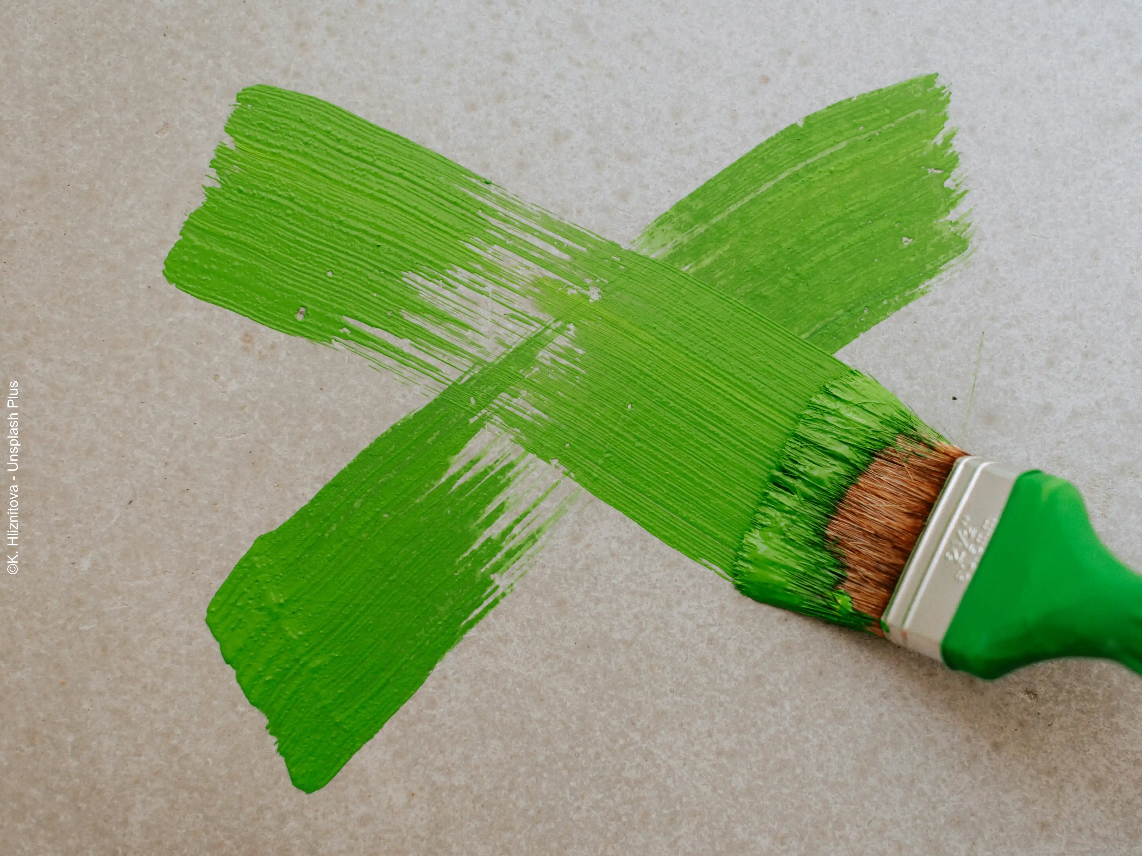 Auf eine Wand wird mit grüner Farbe ein X gemalt